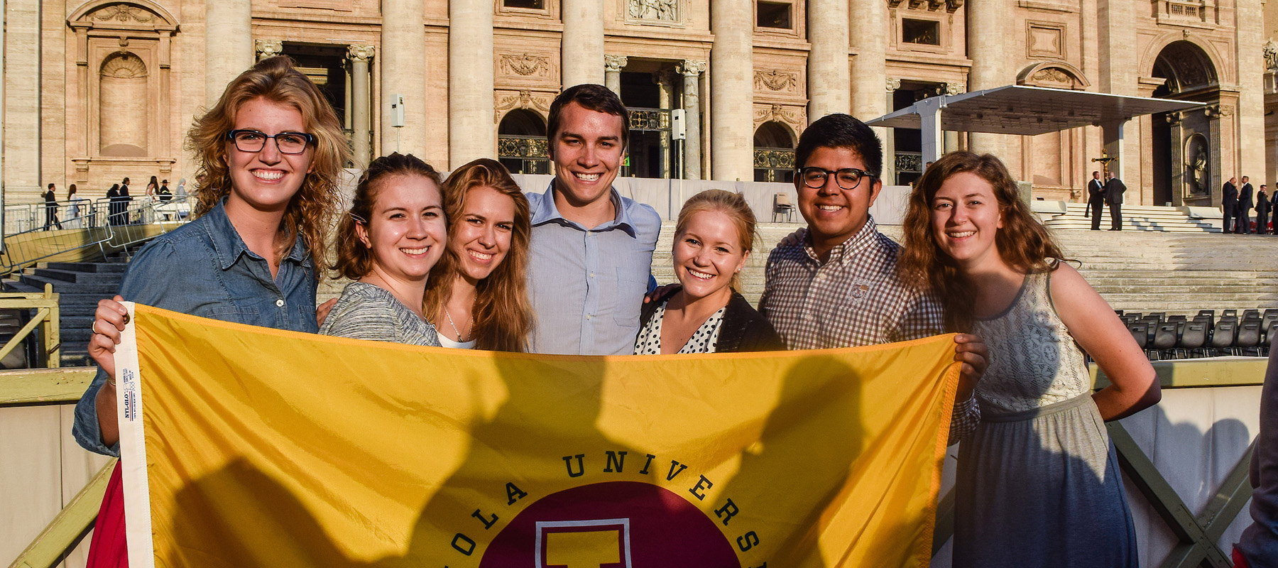 Group of Loyola Chicago students gathered indoors holding a large banner